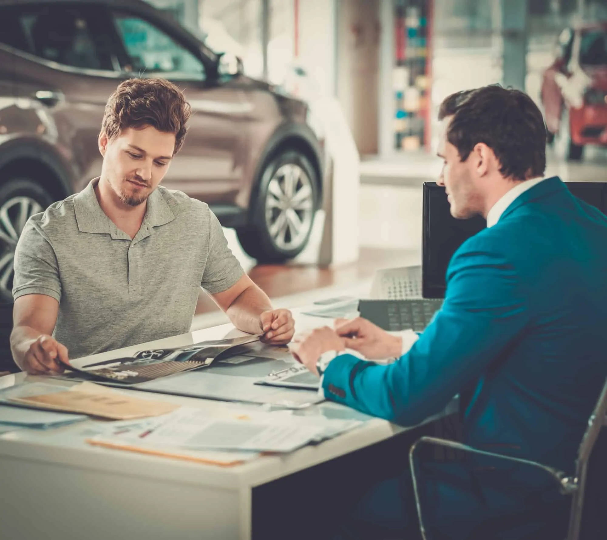 Handsome young man reading a booklet at the dealership showroom.